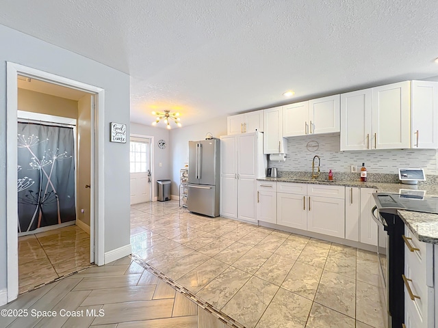1760 Tee Dee Ln, Titusville, FL 32780 - kitchen featuring white cabinets, a sink, range with electric stovetop, backsplash, and freestanding refrigerator
