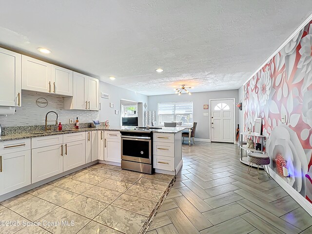 1760 Tee Dee Ln, Titusville, FL 32780 - kitchen with stainless steel range with electric stovetop, white cabinets, a peninsula, a sink, and backsplash