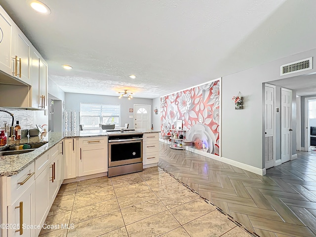 1760 Tee Dee Ln, Titusville, FL 32780 - kitchen featuring a sink, stainless steel range with electric cooktop, a peninsula, visible vents, and decorative backsplash