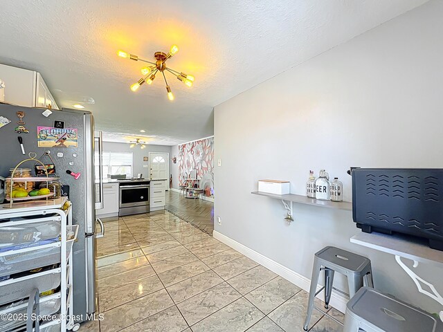 1760 Tee Dee Ln, Titusville, FL 32780 - kitchen with a textured ceiling, white cabinets, baseboards, and appliances with stainless steel finishes