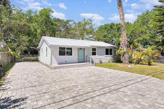 view of front of property with a front yard, fence, and metal roof