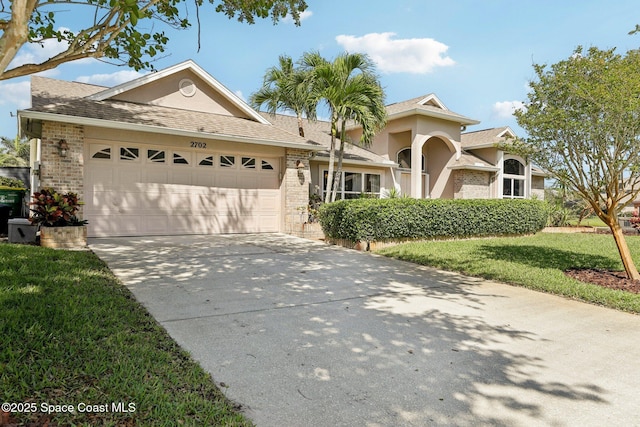 2702 Barrow Dr, Merritt Island, FL 32952 - view of front facade featuring an attached garage, brick siding, a front lawn, driveway, and a shingled roof