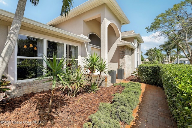2702 Barrow Dr, Merritt Island, FL 32952 - view of home's exterior with cooling unit, stucco siding, and brick siding
