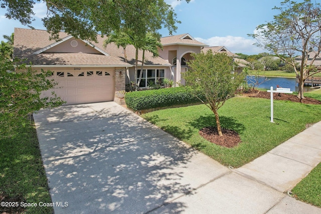 2702 Barrow Dr, Merritt Island, FL 32952 - view of front of property featuring stone siding, a water view, an attached garage, concrete driveway, and a front lawn