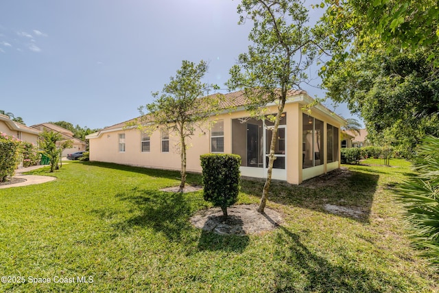 back of house featuring a yard, stucco siding, a sunroom, and a tile roof