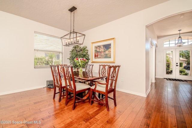 dining area featuring a chandelier, arched walkways, baseboards, and hardwood / wood-style floors