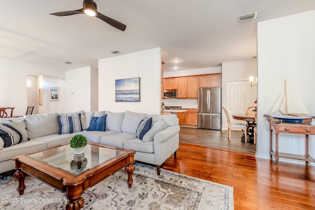 living room with light wood-style floors, a ceiling fan, and visible vents