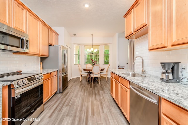 kitchen featuring baseboards, an inviting chandelier, a sink, light wood-type flooring, and appliances with stainless steel finishes