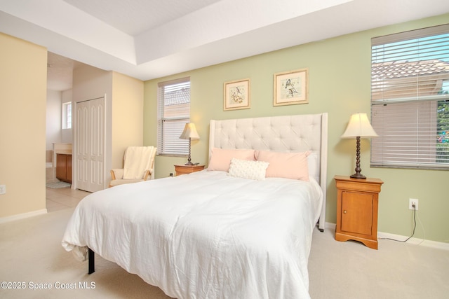 carpeted bedroom with baseboards, multiple windows, and ensuite bath
