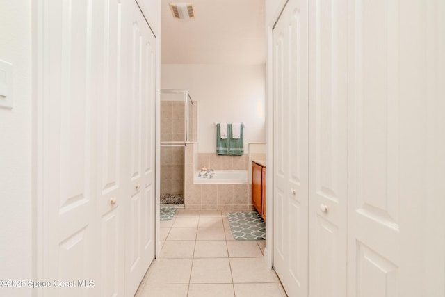 full bathroom featuring a closet, tile patterned floors, a shower stall, visible vents, and a bath