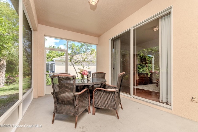 sunroom / solarium with a textured wall and outdoor dining area