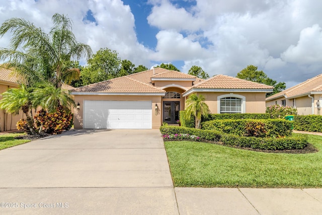 mediterranean / spanish house with a tiled roof, a garage, stucco siding, a front lawn, and driveway