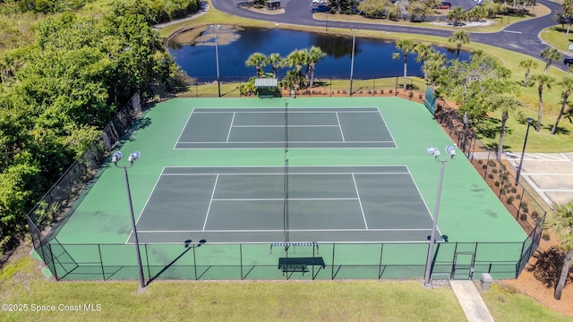 view of tennis court with a yard, a water view, and fence
