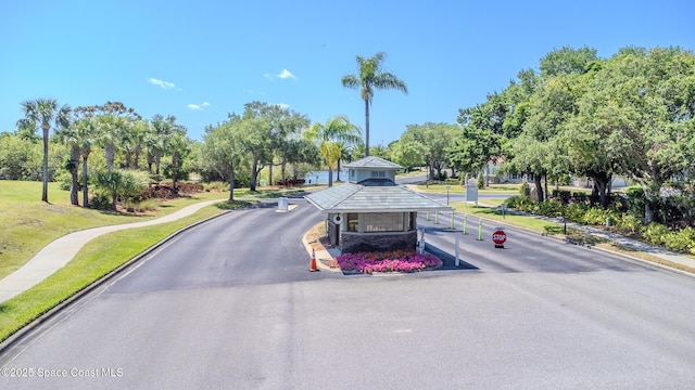 view of road featuring a gated entry, curbs, and sidewalks