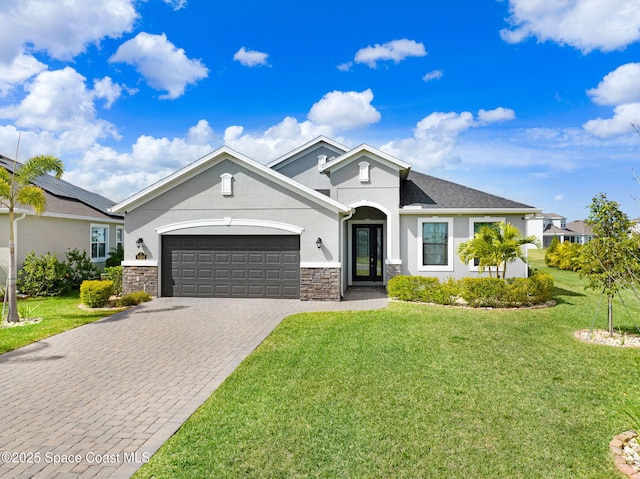 ranch-style house with stucco siding, stone siding, decorative driveway, a front yard, and a garage