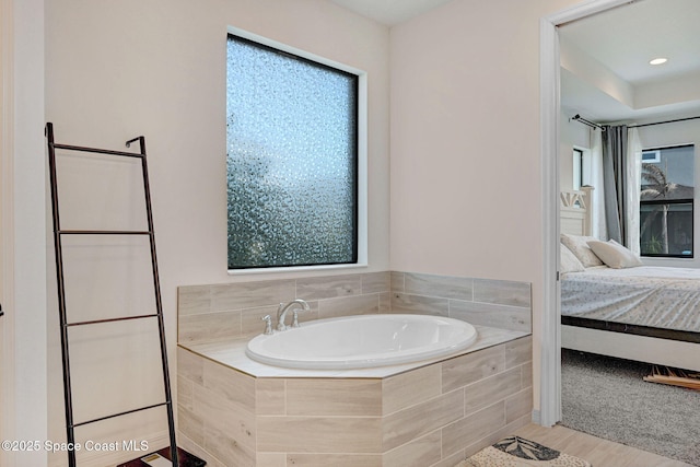 bathroom with ensuite bath, a garden tub, and wood finished floors