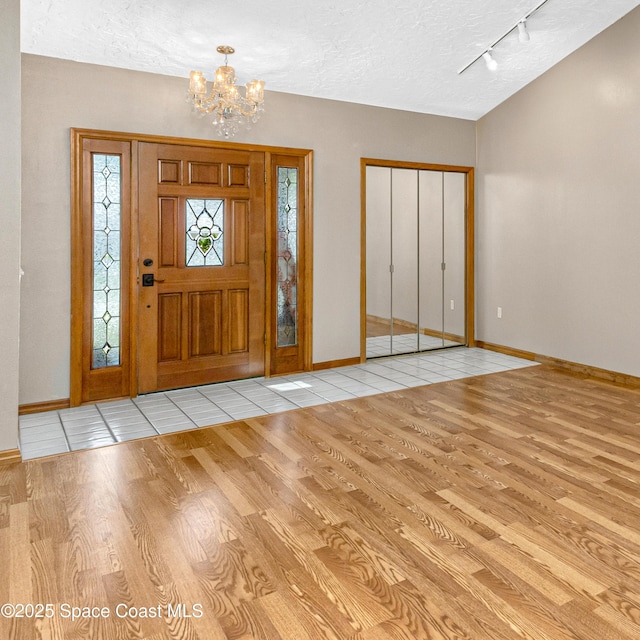 523 Hidden Hollow Dr, Merritt Island, FL 32952 - foyer entrance with an inviting chandelier, a textured ceiling, baseboards, and wood finished floors