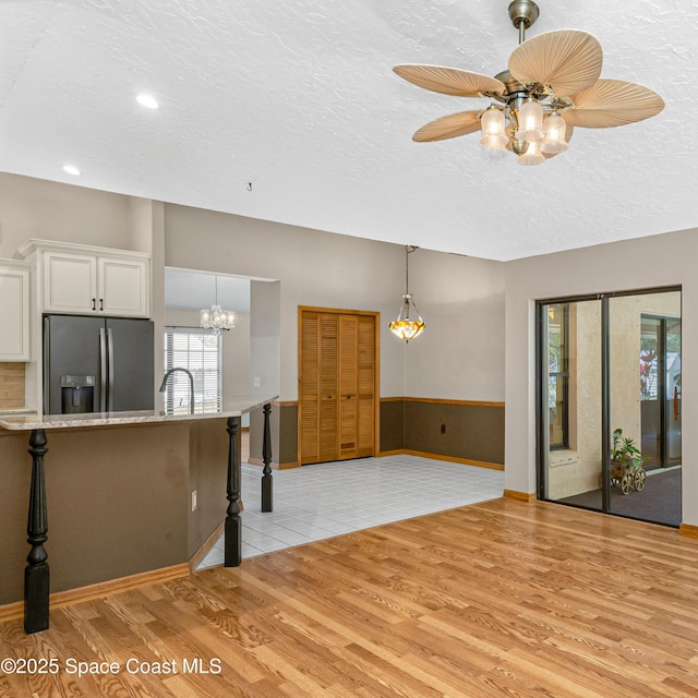 523 Hidden Hollow Dr, Merritt Island, FL 32952 - kitchen with a textured ceiling, white cabinetry, stainless steel refrigerator with ice dispenser, light wood-type flooring, and a breakfast bar area