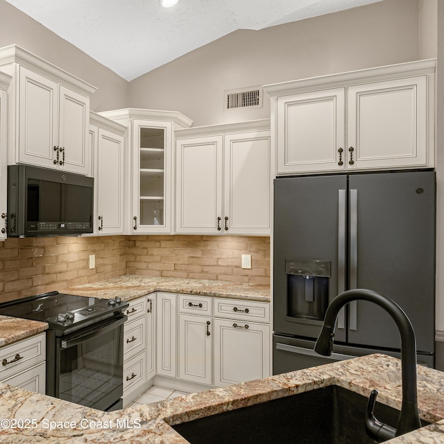 523 Hidden Hollow Dr, Merritt Island, FL 32952 - kitchen featuring light stone countertops, black appliances, lofted ceiling, and visible vents