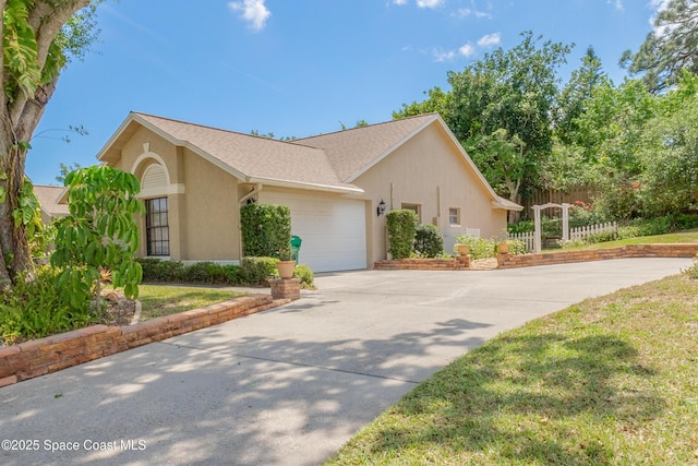 523 Hidden Hollow Dr, Merritt Island, FL 32952 - view of home's exterior featuring concrete driveway, stucco siding, fence, a shingled roof, and a garage