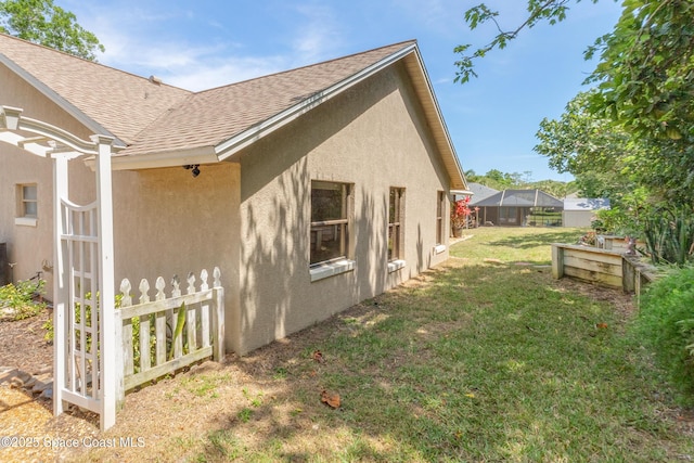 523 Hidden Hollow Dr, Merritt Island, FL 32952 - view of side of property featuring stucco siding, a shingled roof, fence, and a lawn