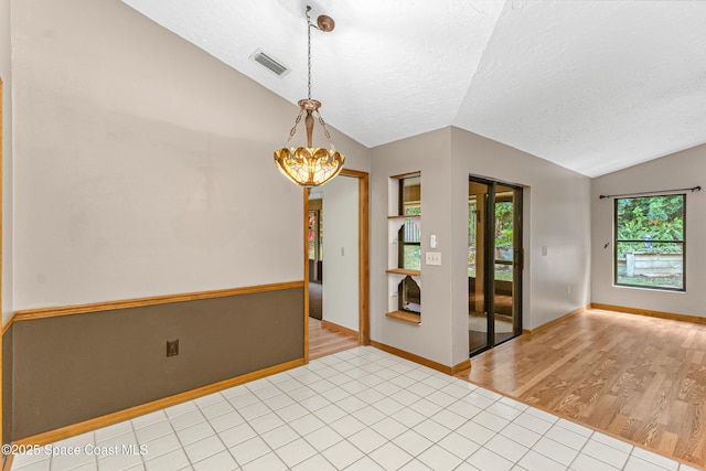 523 Hidden Hollow Dr, Merritt Island, FL 32952 - empty room with a textured ceiling, visible vents, light wood finished floors, an inviting chandelier, and vaulted ceiling