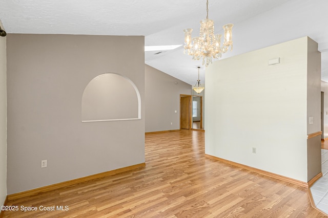 523 Hidden Hollow Dr, Merritt Island, FL 32952 - unfurnished room featuring baseboards, lofted ceiling, wood finished floors, and a chandelier