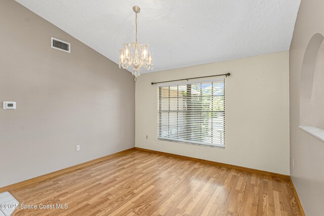 523 Hidden Hollow Dr, Merritt Island, FL 32952 - spare room featuring visible vents, light wood finished floors, arched walkways, lofted ceiling, and a notable chandelier