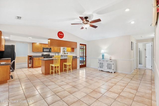 kitchen featuring a kitchen breakfast bar, visible vents, black appliances, vaulted ceiling, and a ceiling fan
