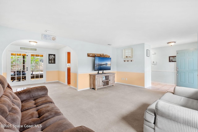 living room featuring carpet floors, baseboards, and arched walkways