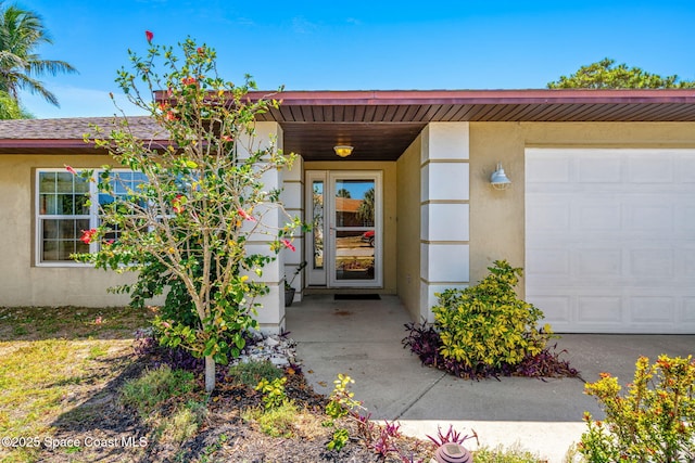 entrance to property featuring stucco siding and an attached garage