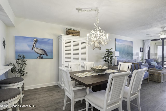 dining space with baseboards, dark wood-style floors, and ceiling fan with notable chandelier