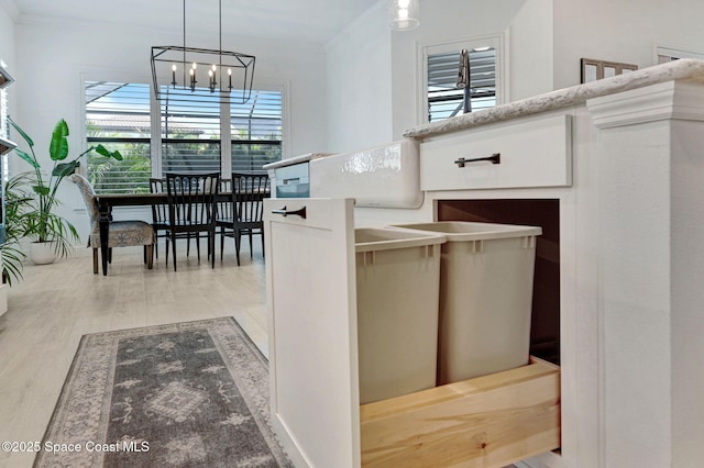 kitchen featuring light wood finished floors, pendant lighting, ornamental molding, and a chandelier