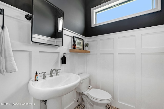 bathroom with a decorative wall, a sink, and toilet