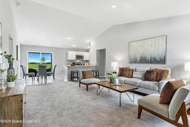 living area featuring baseboards, high vaulted ceiling, recessed lighting, and light colored carpet