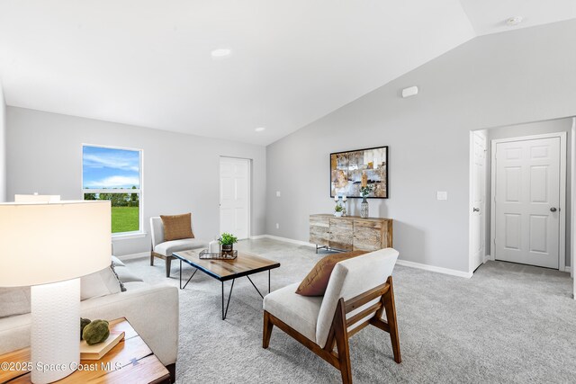 living room featuring baseboards, lofted ceiling, and light colored carpet