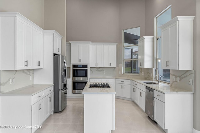 706 Palmer Way, Melbourne, FL 32940 - kitchen featuring appliances with stainless steel finishes, a sink, a high ceiling, tasteful backsplash, and white cabinetry