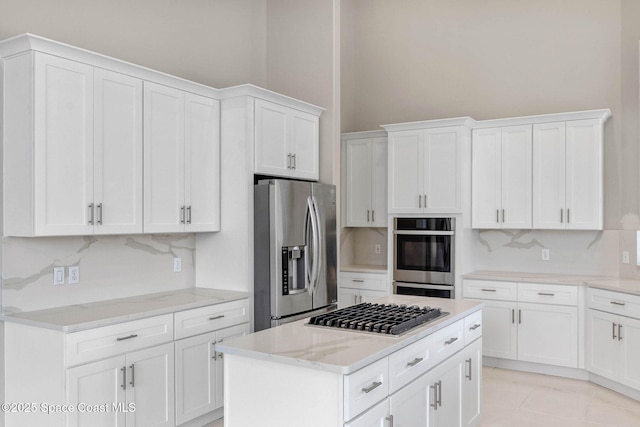 706 Palmer Way, Melbourne, FL 32940 - kitchen featuring stainless steel appliances, decorative backsplash, white cabinets, light stone counters, and a kitchen island