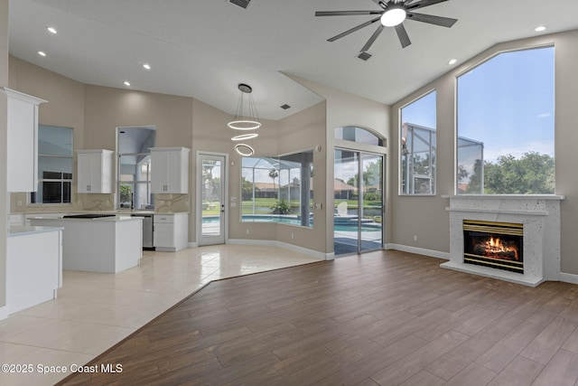 706 Palmer Way, Melbourne, FL 32940 - unfurnished living room with a ceiling fan, a glass covered fireplace, high vaulted ceiling, recessed lighting, and light wood-style flooring