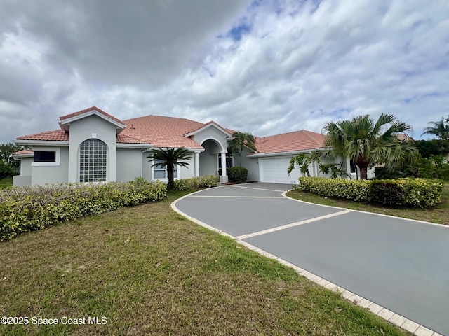 706 Palmer Way, Melbourne, FL 32940 - mediterranean / spanish-style house featuring a tiled roof, asphalt driveway, a garage, stucco siding, and a front yard
