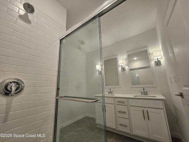 bathroom with double vanity, a sink, tile patterned floors, and tiled shower