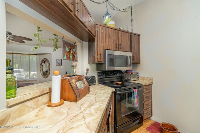 1666 Yamada St SE, Palm Bay, FL 32909 - kitchen featuring black range with electric cooktop, brown cabinets, ceiling fan, light countertops, and stainless steel microwave