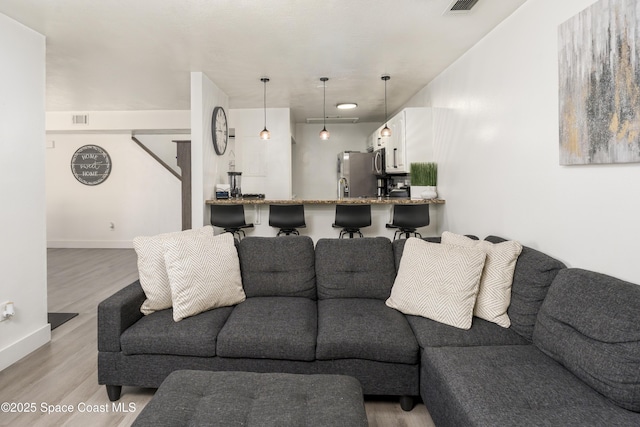 living area featuring baseboards, visible vents, and light wood finished floors