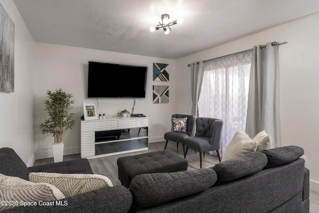 living area with baseboards, wood finished floors, and a textured ceiling