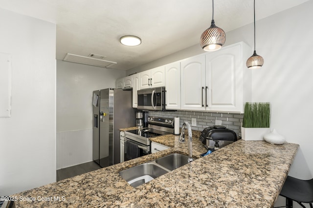 kitchen with white cabinets, stainless steel appliances, tasteful backsplash, dark stone countertops, and a sink