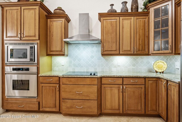 129 Lancha Cir Unit 201, Indian Harbour Beach, FL 32937 - kitchen featuring glass insert cabinets, light stone countertops, wall chimney range hood, and appliances with stainless steel finishes