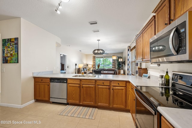 3666 Mount Carmel Ln, Melbourne, FL 32901 - kitchen with appliances with stainless steel finishes, a sink, brown cabinetry, and a peninsula