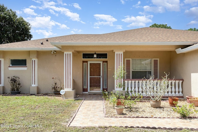 2298 Mantilla Ave SE, Palm Bay, FL 32909 - property entrance with a shingled roof, a lawn, stucco siding, and covered porch
