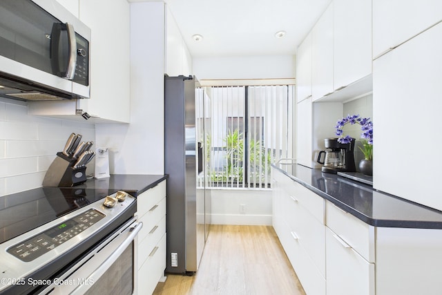 6365 Bahia Del Mar Blvd S Unit 210, Saint Petersburg, FL 33710 - kitchen with stainless steel appliances, dark countertops, white cabinetry, light wood-style floors, and backsplash