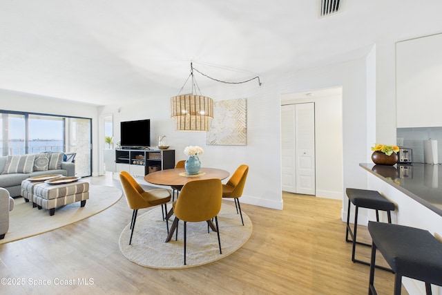 6365 Bahia Del Mar Blvd S Unit 210, Saint Petersburg, FL 33710 - dining area featuring baseboards, visible vents, a notable chandelier, and light wood-type flooring